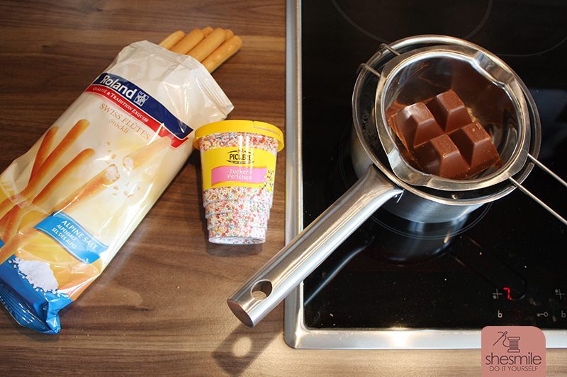 Du brauchst: Eine Packung Grissini-Stangen, bunte Zuckerperlen, eine Packung Blockschokolade zum Schmelzen