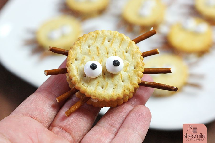 Alles was du brauchst sind Cracker-Kekse, Salzstangen, Augen und eine streichbare Creme. Damit erstellst du lustige Spinnen-Cracker für die Kinder-Halloween-Party. Eine Idee von shesmile.de